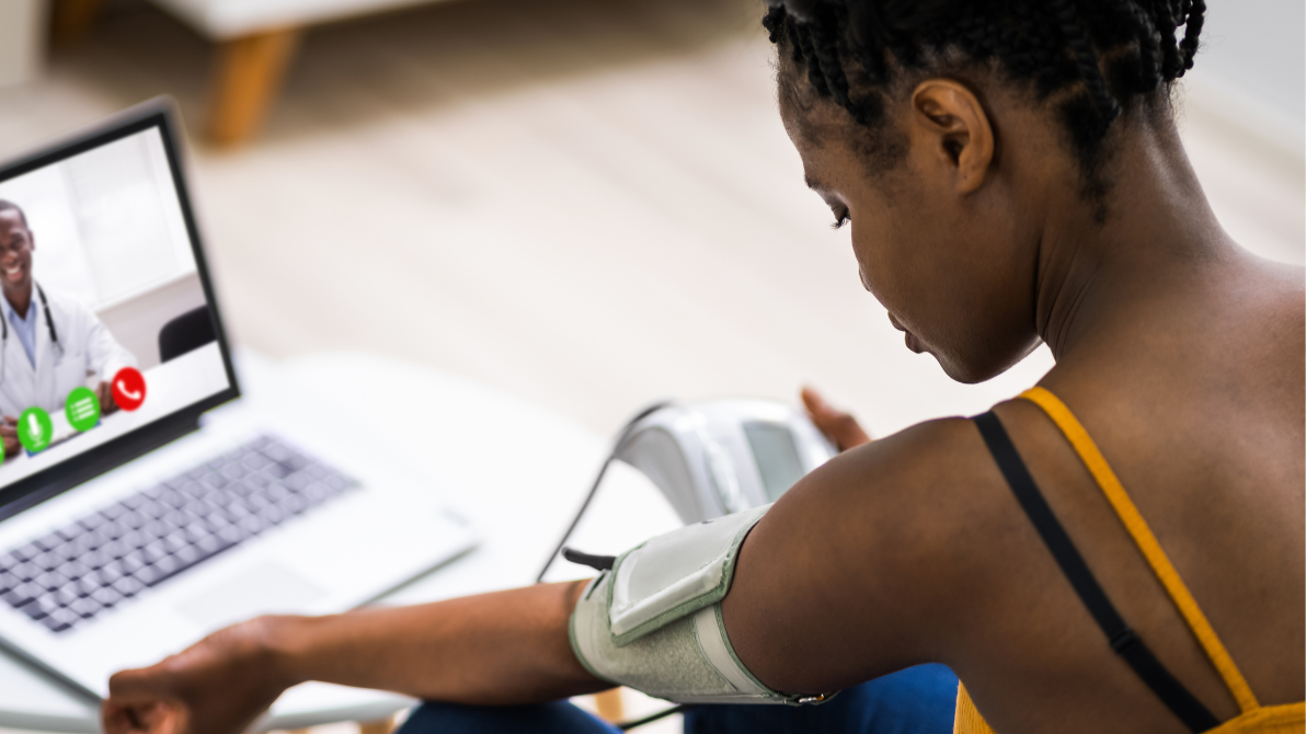 A woman wearing a blood pressure monitor on an online call with a doctor