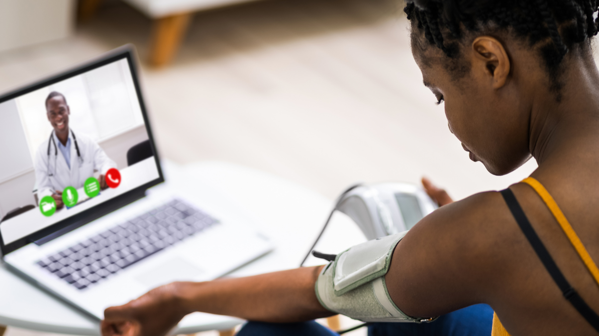 A woman wearing a blood pressure monitor on an online call with a doctor