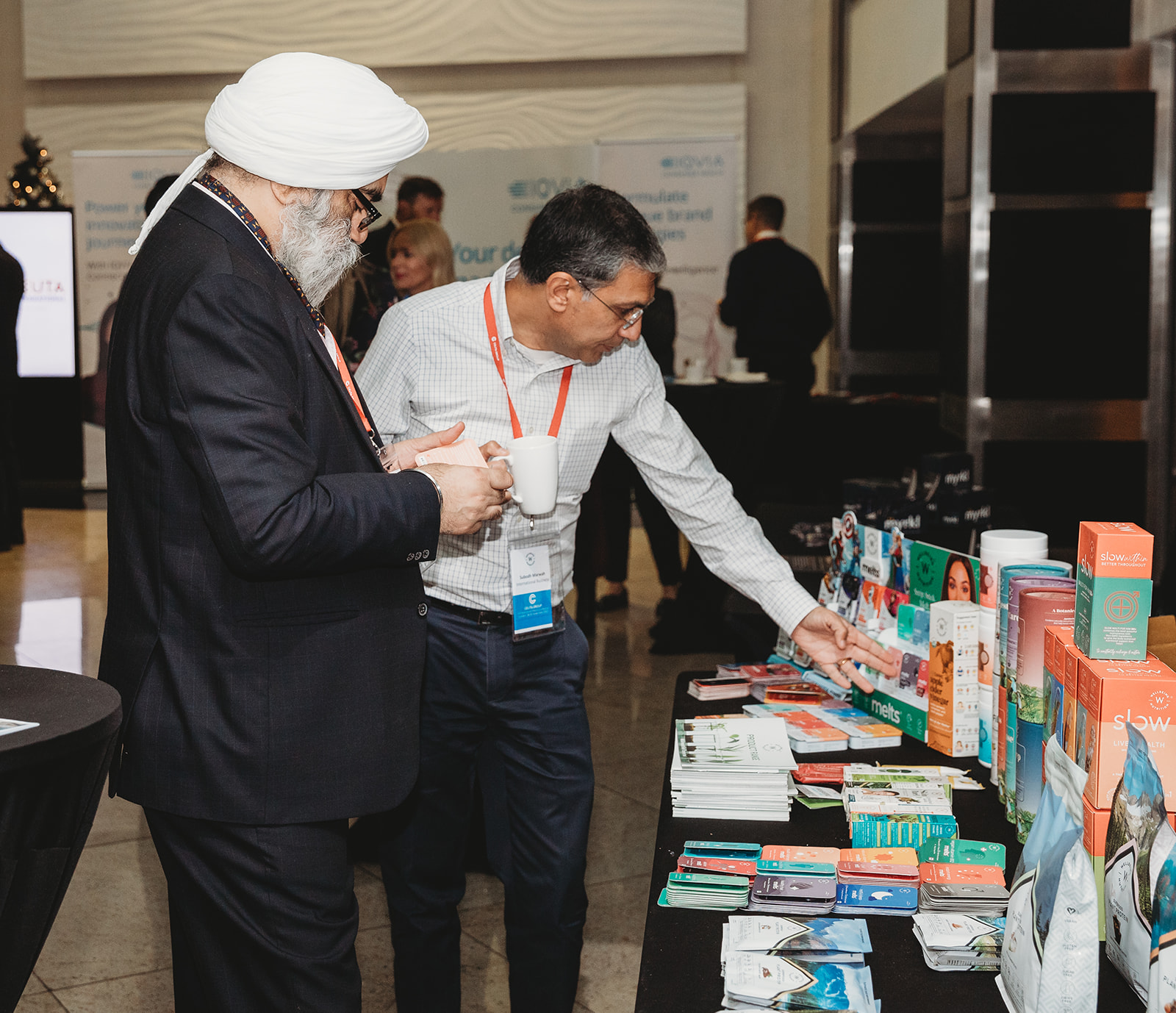 Two people pick up various healthcare product samples from a desk at the Ceuta International conference