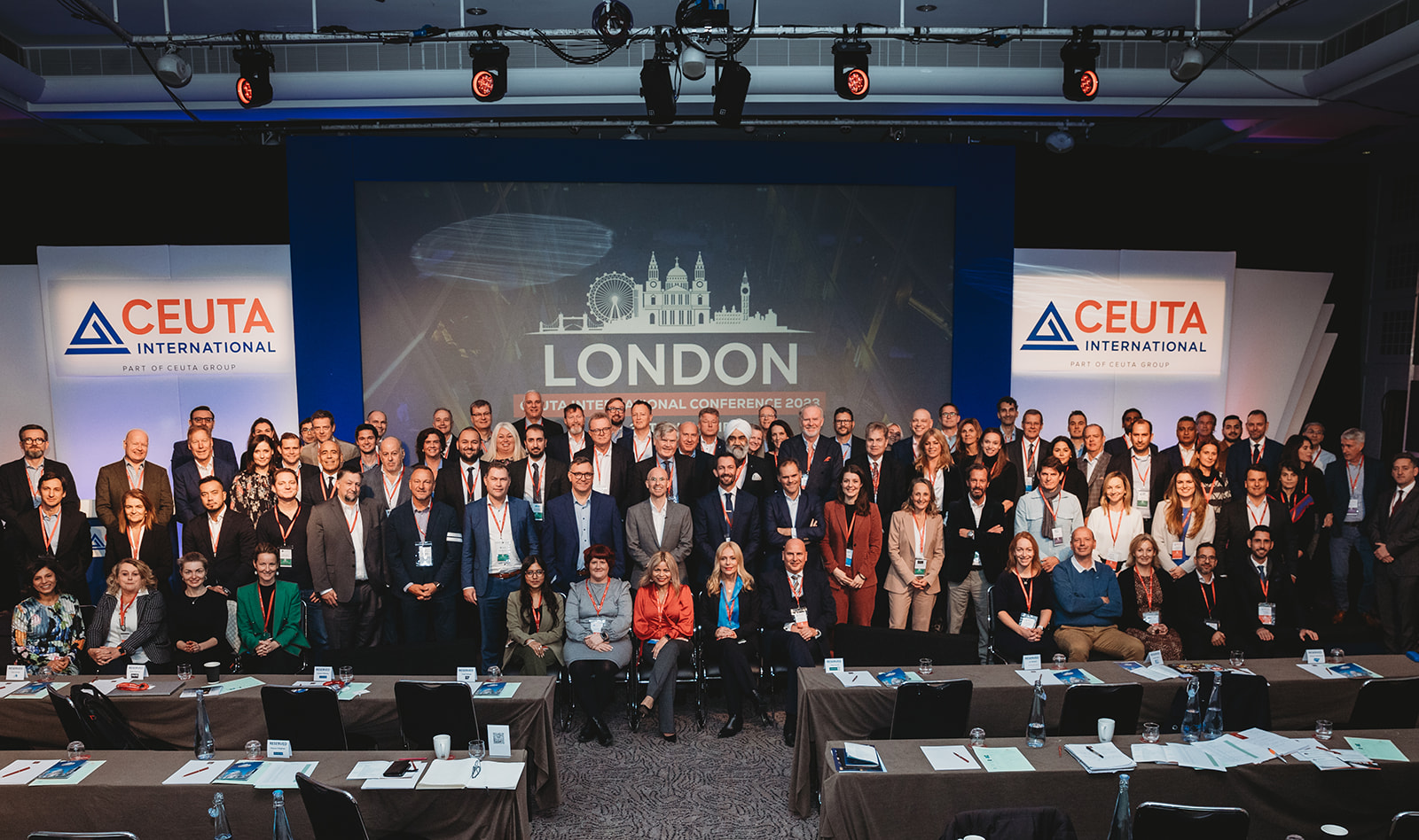 A group of people in business attire standing and sitting together on the Ceuta International Conference stage