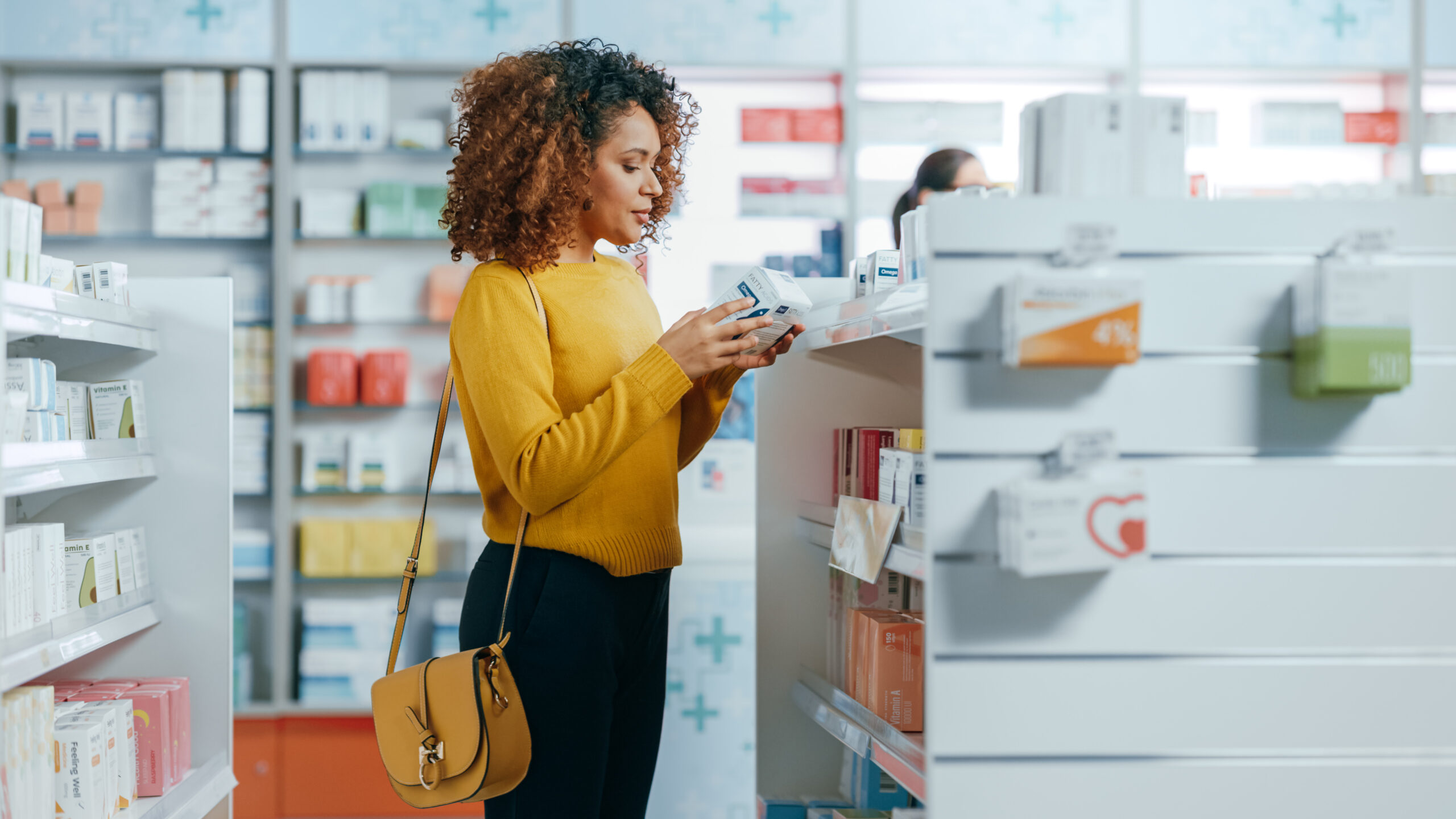 A woman in a yellow top looking at a product in a pharmacy