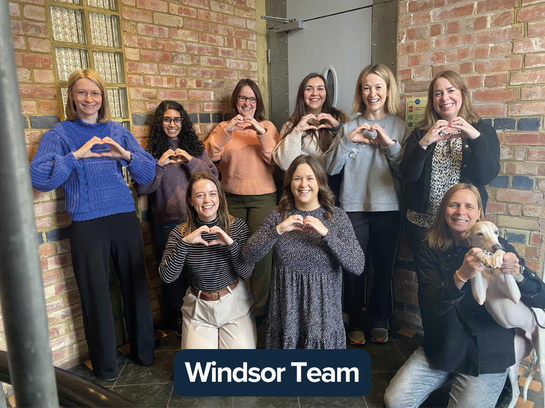 A group of people and a dog making a heart with their hands