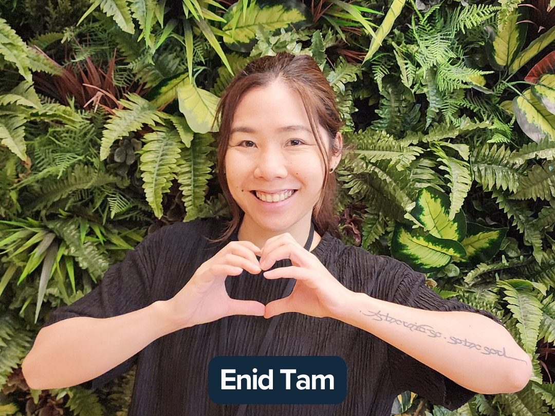 Enid Tam making a heart pose with their hands