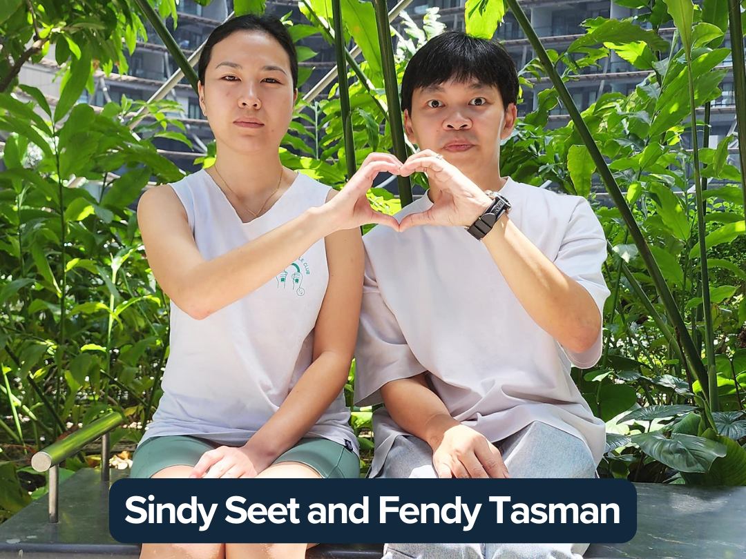 Sindy Seet and Fendy Tasman sit together making a heart pose with their hands